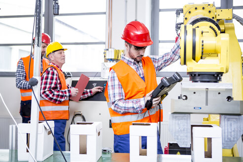 Drei Männer in einer Fabrik mit Industrieroboter - WESTF23429