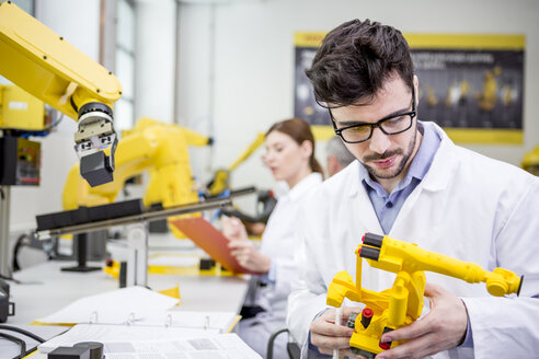 Engineer holding model of an industrial robot - WESTF23437