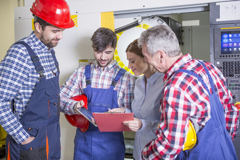 Staff discussing in factory with CNC machine in background - WESTF23438