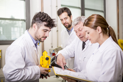 Engineers with industrial robot model checking documents stock photo