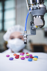 Robot handling sweets with woman in background - WESTF23467