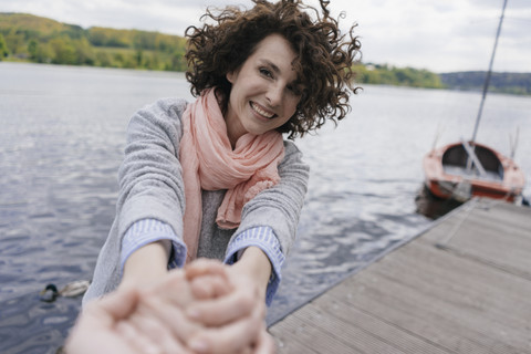 Frau auf Steg stehend, an der Hand eines Mannes ziehend, lizenzfreies Stockfoto