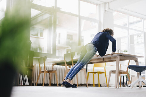 Businesswoman in office doing push ups on desk - KNSF01556