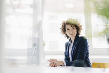 Businesswoman in office sitting at desk - KNSF01563