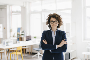 Businesswoman standing in her office with arms crossed - KNSF01566