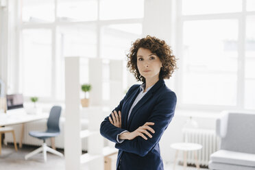 Businesswoman standing in her office with arms crossed - KNSF01568