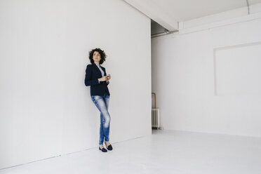 Businesswoman standing in loft , leaning against wall - KNSF01569