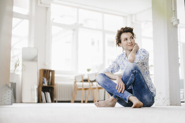 Frau sitzt auf dem Boden in ihrer Wohnung - KNSF01591