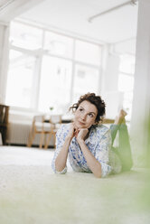 Frau liegt in ihrer Wohnung auf dem Boden und denkt nach - KNSF01593