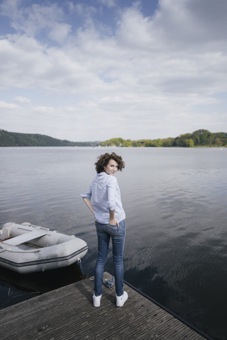 Woman standing on jetty with moored boat stock photo