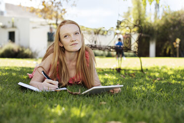 Grl mit langen roten Haaren im Gras liegend mit Tablet und Notizbuch - ZEF13931