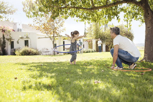 Vater und Tochter mit Hula-Hoop-Reifen im Gras - ZEF13936