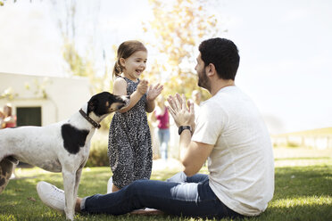 Happy father, daughter and dog in garden - ZEF13939