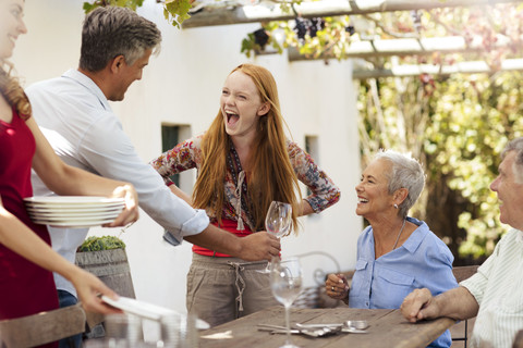 Glückliche Familie deckt den Tisch draußen für das Mittagessen, lizenzfreies Stockfoto