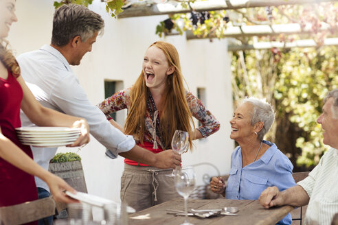 Glückliche Familie deckt den Tisch draußen für das Mittagessen - ZEF13964