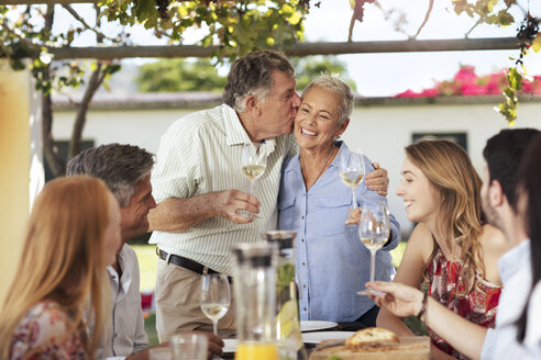 Glückliches älteres Paar mit Familie beim gemeinsamen Mittagessen im Freien - ZEF13974