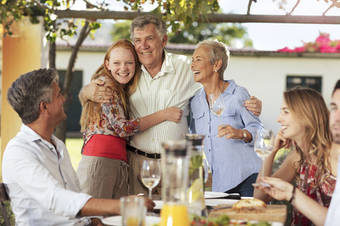 Happy senior couple with family having lunch together outside stock photo