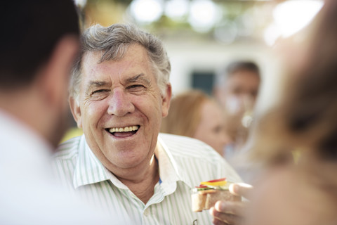 Glücklicher älterer Mann beim geselligen Beisammensein auf einer Gartenparty, lizenzfreies Stockfoto