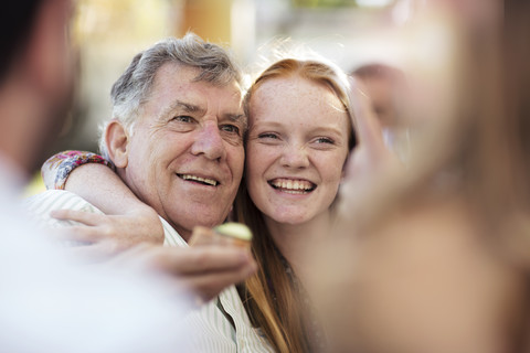 Enkelin umarmt Großvater im Freien, lizenzfreies Stockfoto