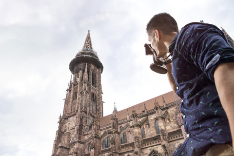 Deutschland, Freiburg, junger Mann beim Fotografieren des Münsters, lizenzfreies Stockfoto