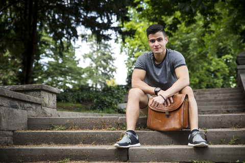 Junger Mann sitzt auf einer Treppe im Park, lizenzfreies Stockfoto