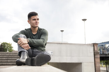 Young man sitting on wall in the city - MIDF00846