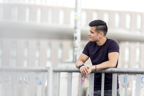 Young man leaning on railing looking away - MIDF00850