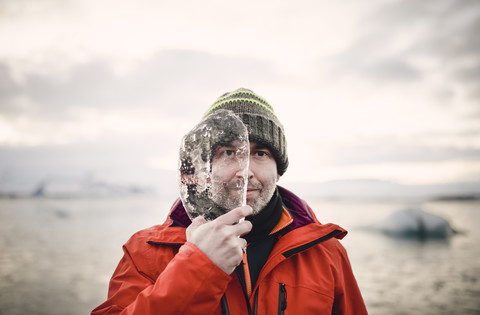 Island, Mann mit einem Stück Eis, das sein halbes Gesicht bedeckt, lizenzfreies Stockfoto