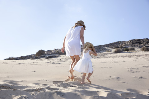 Spanien, Fuerteventura, Mutter geht mit Tochter am Strand spazieren, lizenzfreies Stockfoto