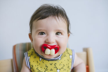 Porträt eines kleinen Mädchens, das an einem Schnuller mit falschen Zähnen und Mund saugt - GEMF01685
