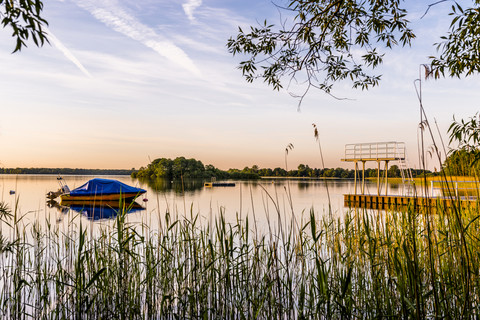 Deutschland, Schaalsee mit vertäutem Motorboot und Highboard in der Abenddämmerung, lizenzfreies Stockfoto