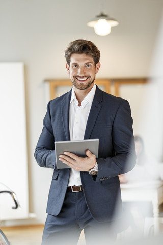 Portrait of confident businessman holding tablet in office stock photo