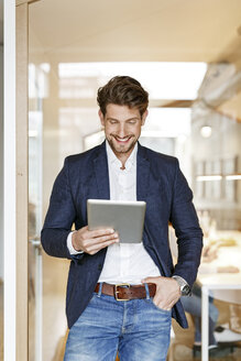 Lächelnder Geschäftsmann mit Tablet im Büro - PESF00650