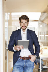 Porträt eines lächelnden Geschäftsmannes, der ein Tablet im Büro benutzt - PESF00651