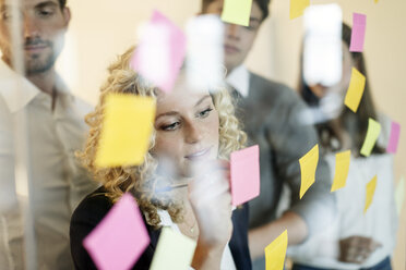 Colleagues in office behind glass pane with adhesive notes - PESF00669