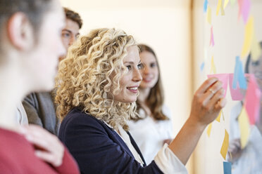 Colleagues in office at glass pane with adhesive notes - PESF00670