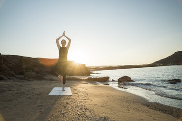 Greece, Crete, woman practicing yoga on the beach at sunset - CHPF00406