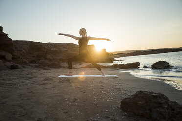 Greece, Crete, woman practicing yoga on the beach at sunset - CHPF00407