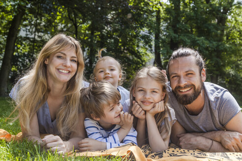 Porträt einer glücklichen Familie auf einer Wiese liegend - TCF05436