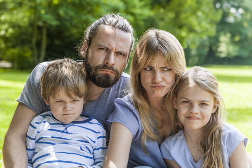 Porträt einer verspielten Familie, die im Freien Gesichter zieht - TCF05443