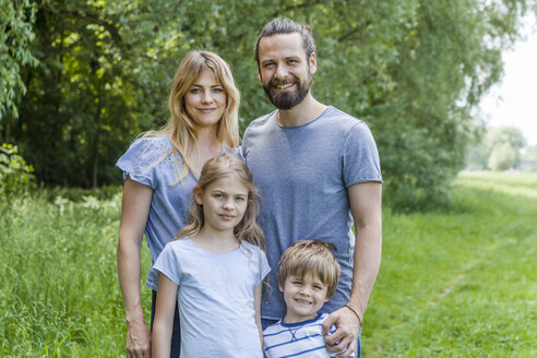 Porträt einer glücklichen Familie auf einer Wiese stehend - TCF05444