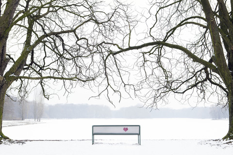 Gesticktes Herz an Bank in Winterlandschaft, lizenzfreies Stockfoto