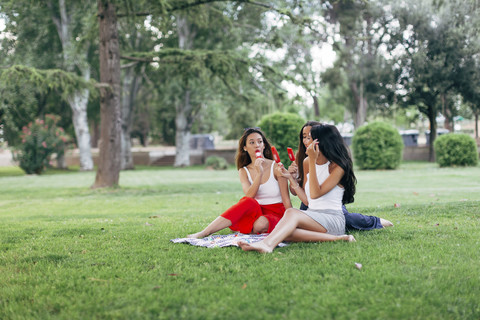 Freunde in einem Park genießen Eis am Stiel, lizenzfreies Stockfoto