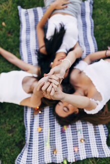 Freunde in einem Park, die auf einer Decke liegen und ihre Arme heben - JPF00227