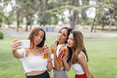 Verspielte Freunde in einem Park, die Bier trinken und ein Selfie machen - JPF00232