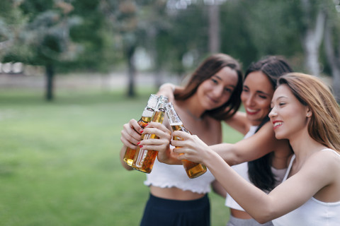 Friends in a park clinking beer bottles stock photo