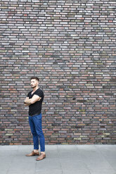 Serious man standing at brick wall - DMOF00017