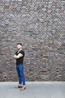 Ernster Mann steht an einer Mauer - DMOF00017