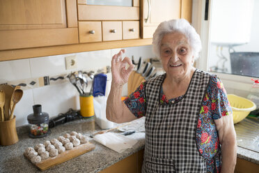 Porträt einer lächelnden älteren Frau, die das Ok-Zeichen in der Küche zeigt - RAEF01893