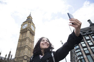 Großbritannien, London, glückliche Frau macht Selfie mit Smartphone vor dem Big Ben - ABZF02102